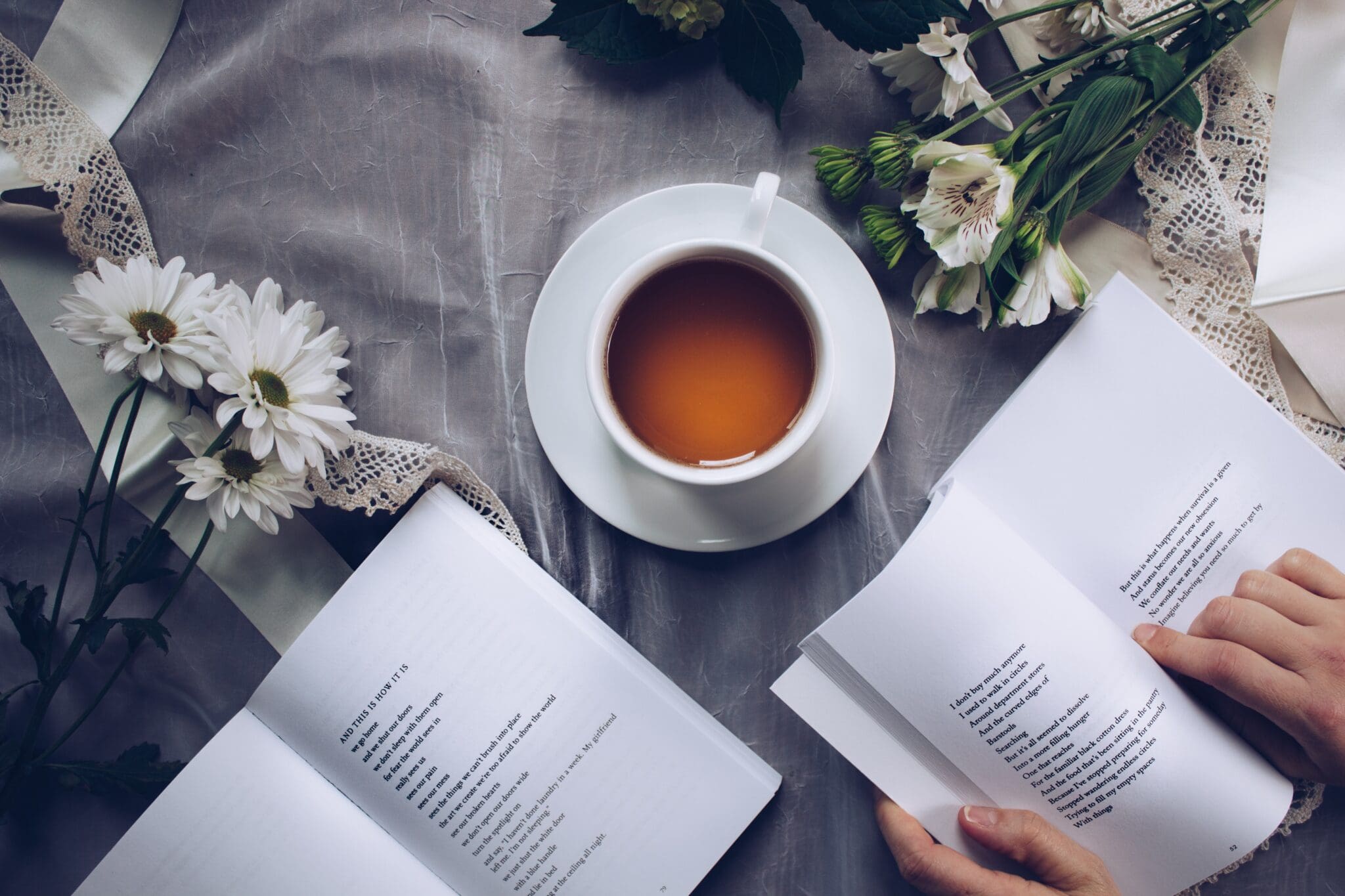 Người đang đọc sách bên cạnh tách cà phê